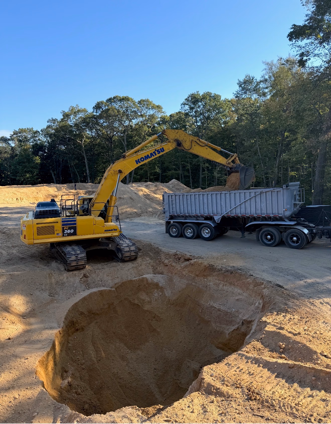 D.C. Crane Service — Komatsu excavator loading fill into a dump truck