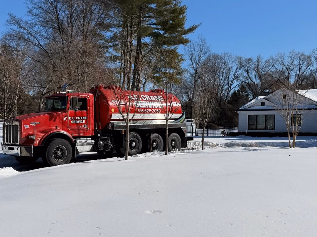 D.C. Crane Service — branded septic pumping truck on a residential call, Long Island NY
